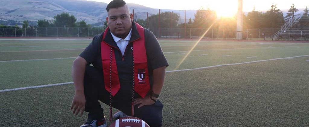 SOU Graduate Spotlight Jose Angel Stephen-Herman kneeling on football field at Southern Oregon University Learn More
